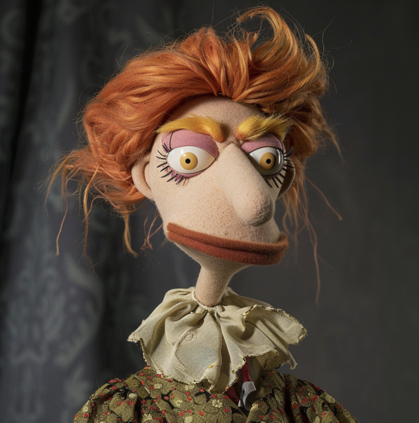 Muppet with wavy red hair, wide thin lips, ruffled collar, and patterned dress