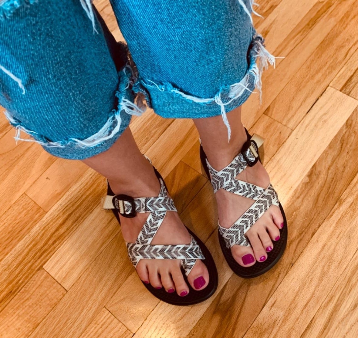 Person wearing frayed jeans and patterned sandals