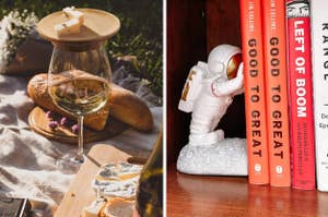 glass of wine with bamboo coaster holding cheese on top and reviewers astronaut figurine holding up books