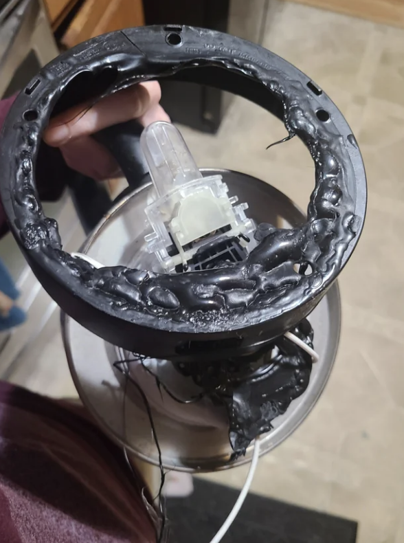 Person holding a severely damaged and melted gaming steering wheel controller