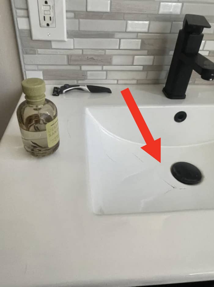 Bathroom sink with a bottle of Dr Teal&#x27;s body oil and a black faucet