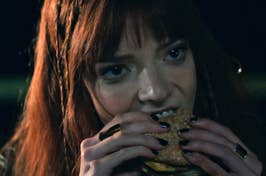 Anya Taylor Joy eating a burger as Margot in The Menu