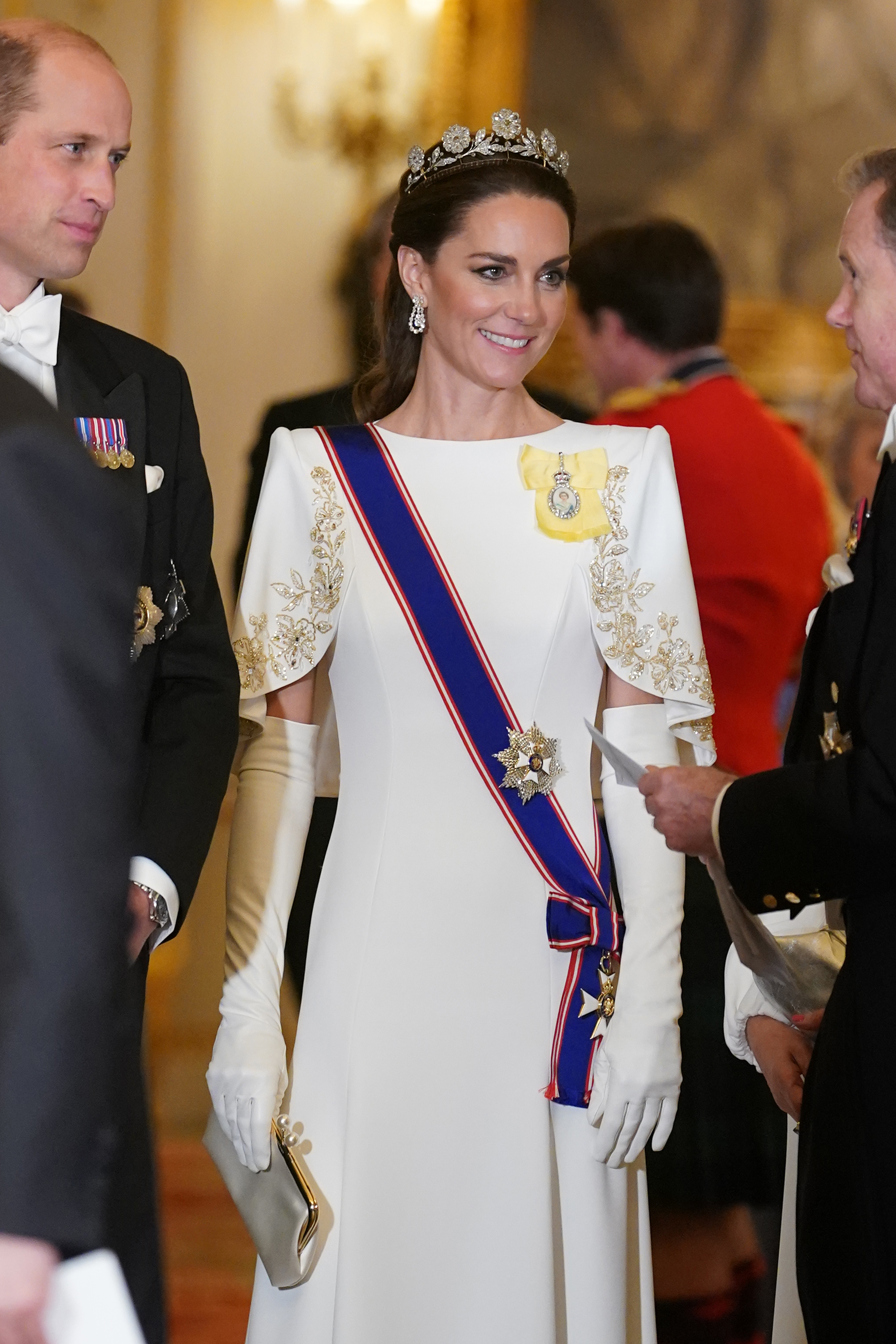 Kate Middleton in a gown with embroidered sleeves and a tiara, at a formal event