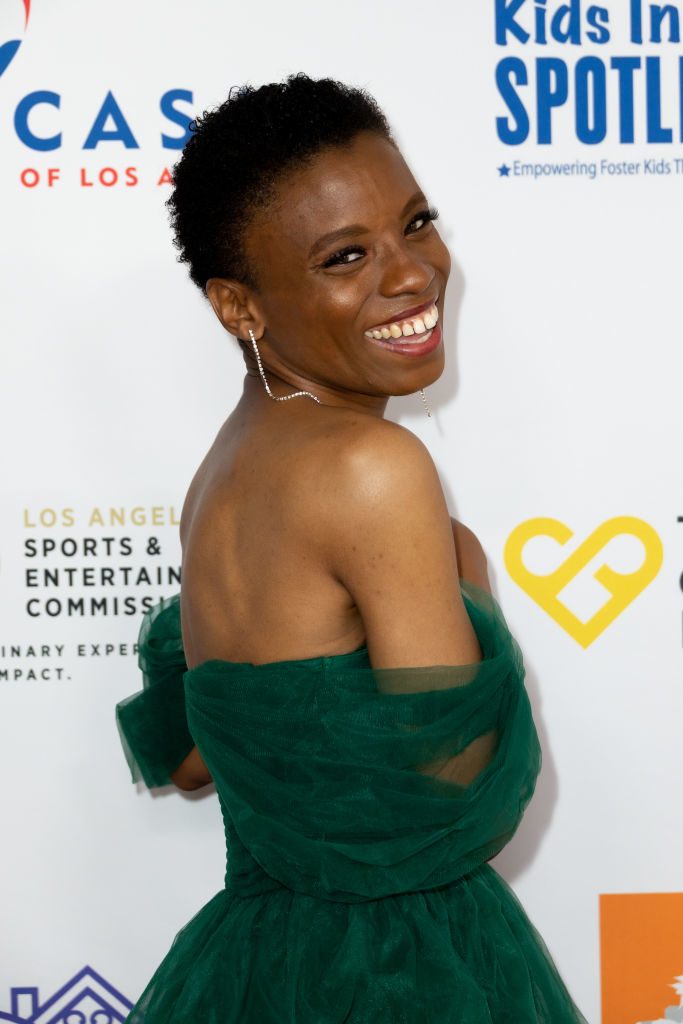 Angelique in a green off-the-shoulder dress posing with a smile at an event