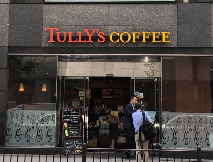 タリーズコーヒー店舗の外観、入口に立つ人とメニュー看板。