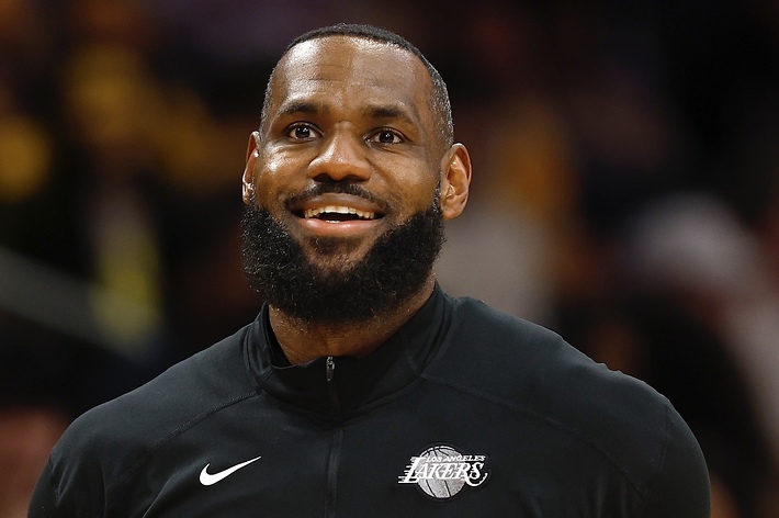 LeBron James in a Lakers Nike warm-up outfit, smiling on the basketball court