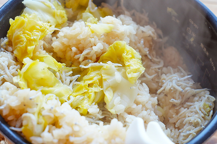 湯気が立つご飯にキャベツとエノキダケがのった炊き込みご飯です。