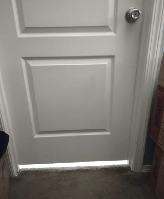 Closed door with light shining underneath showing a gap where sound and light come in