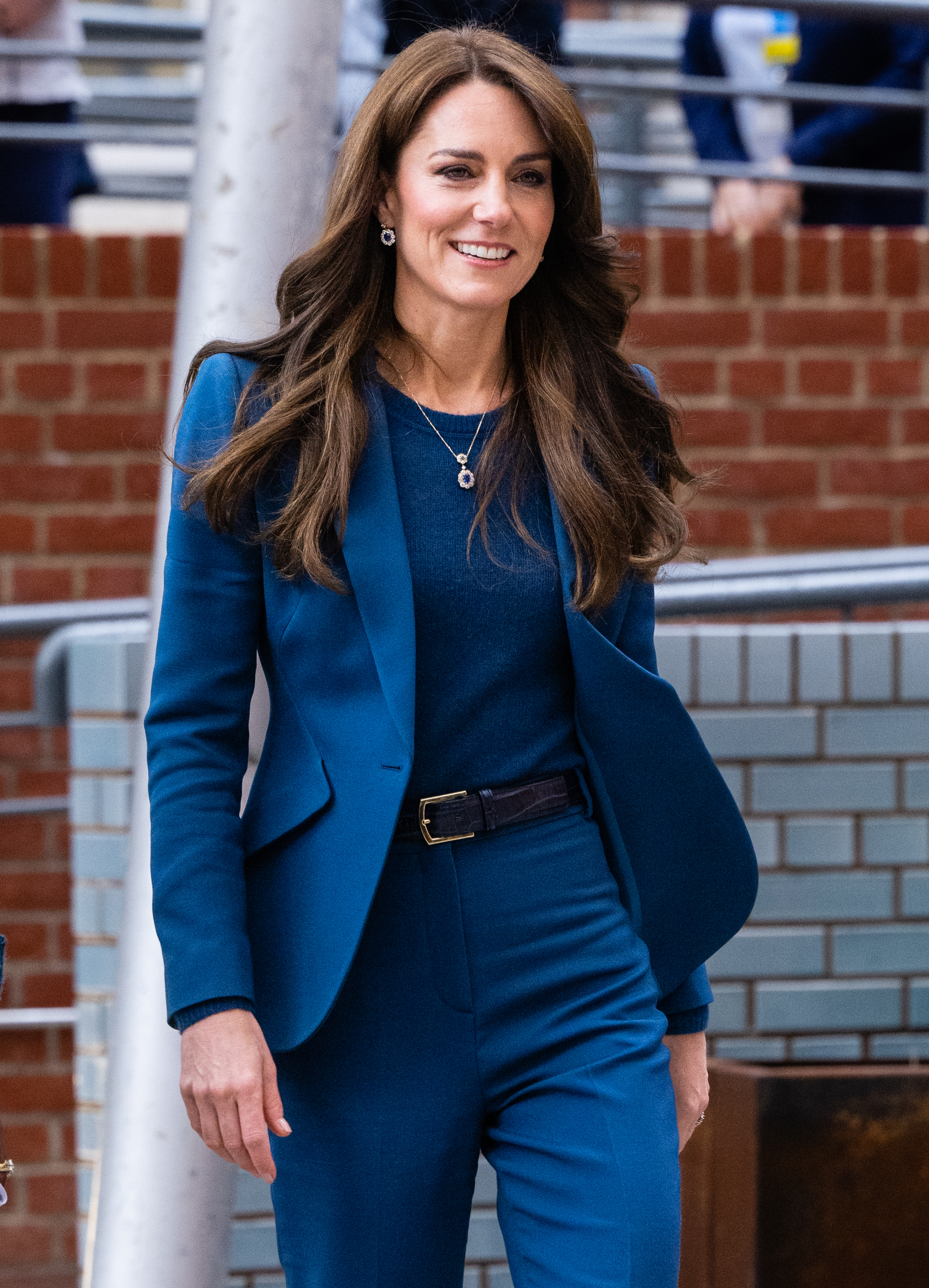 Kate in a tailored blue blazer and trousers with a smile, walking outdoors
