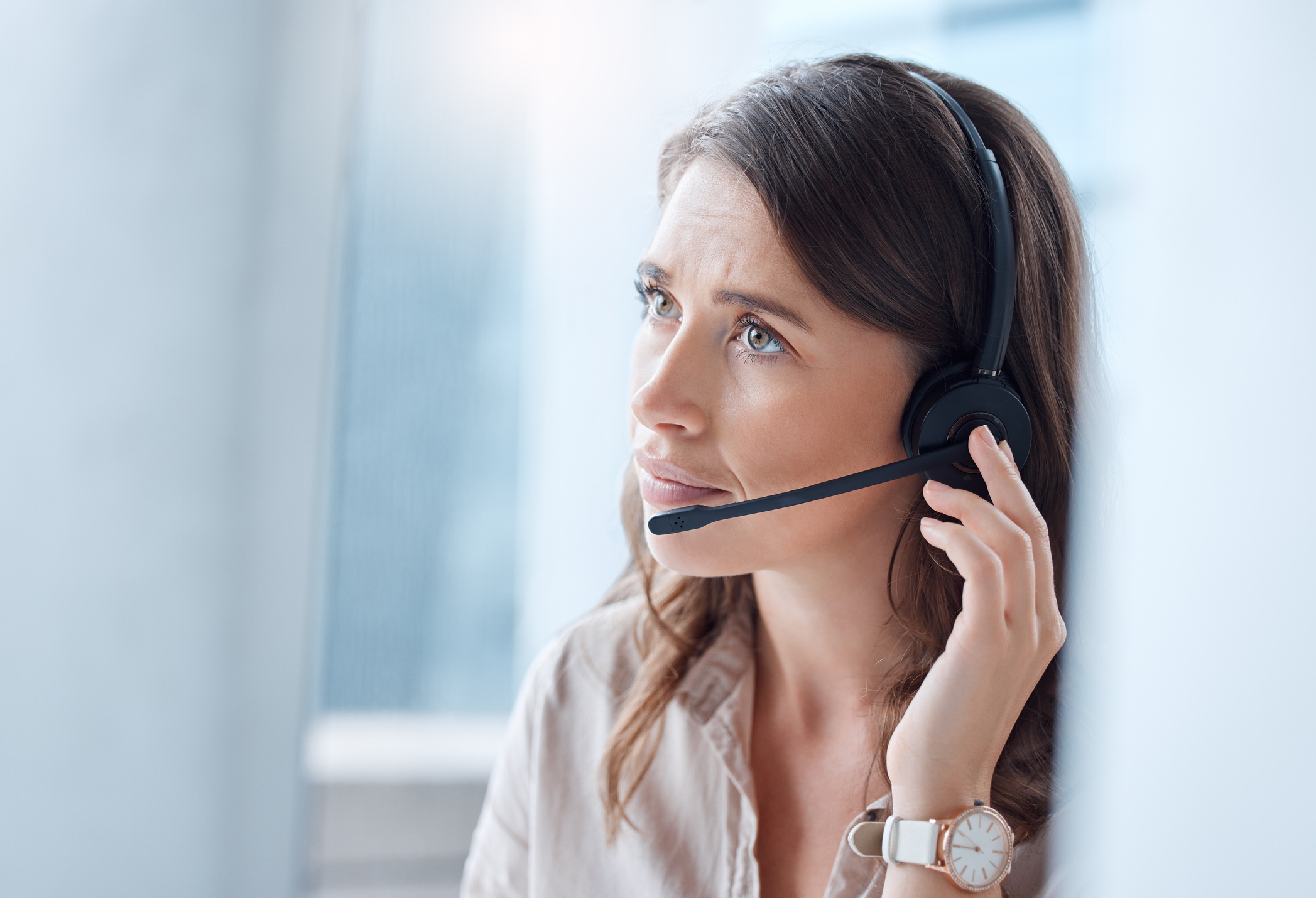 Woman with headset looking thoughtful, likely representing customer service or office work