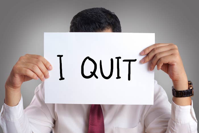 Person holding a sign that reads &quot;I QUIT&quot; in front of their face, indicating resignation from a job