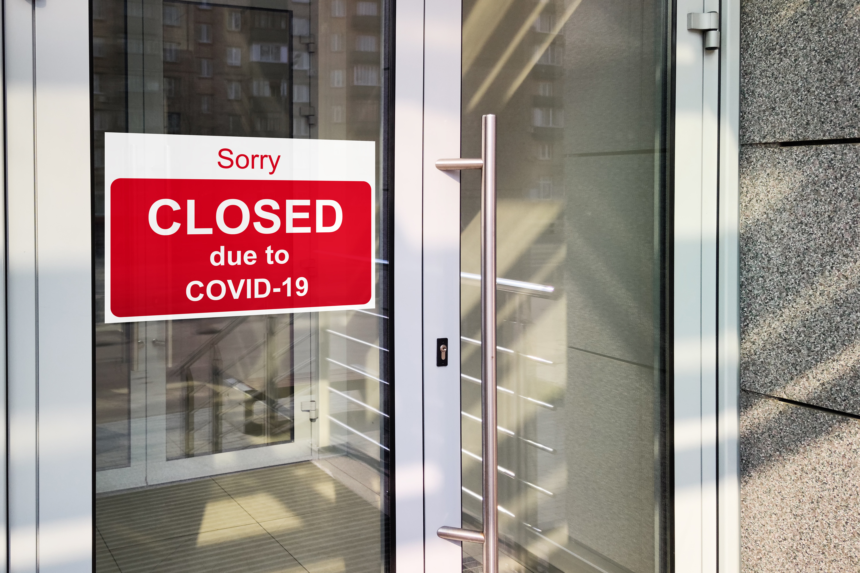 Sign on business door reads &quot;Sorry CLOSED due to COVID-19&quot; indicating temporary closure