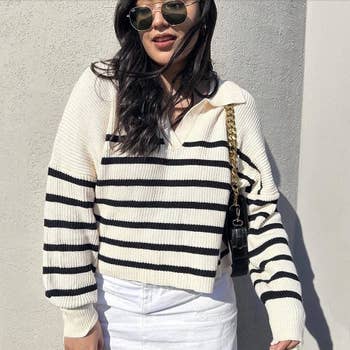 reviewer in a striped sweater and sunglasses posing with a shoulder bag