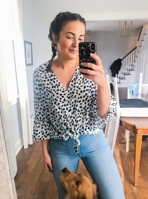 a reviewer in a polka dot top and jeans taking a mirror selfie with her dog