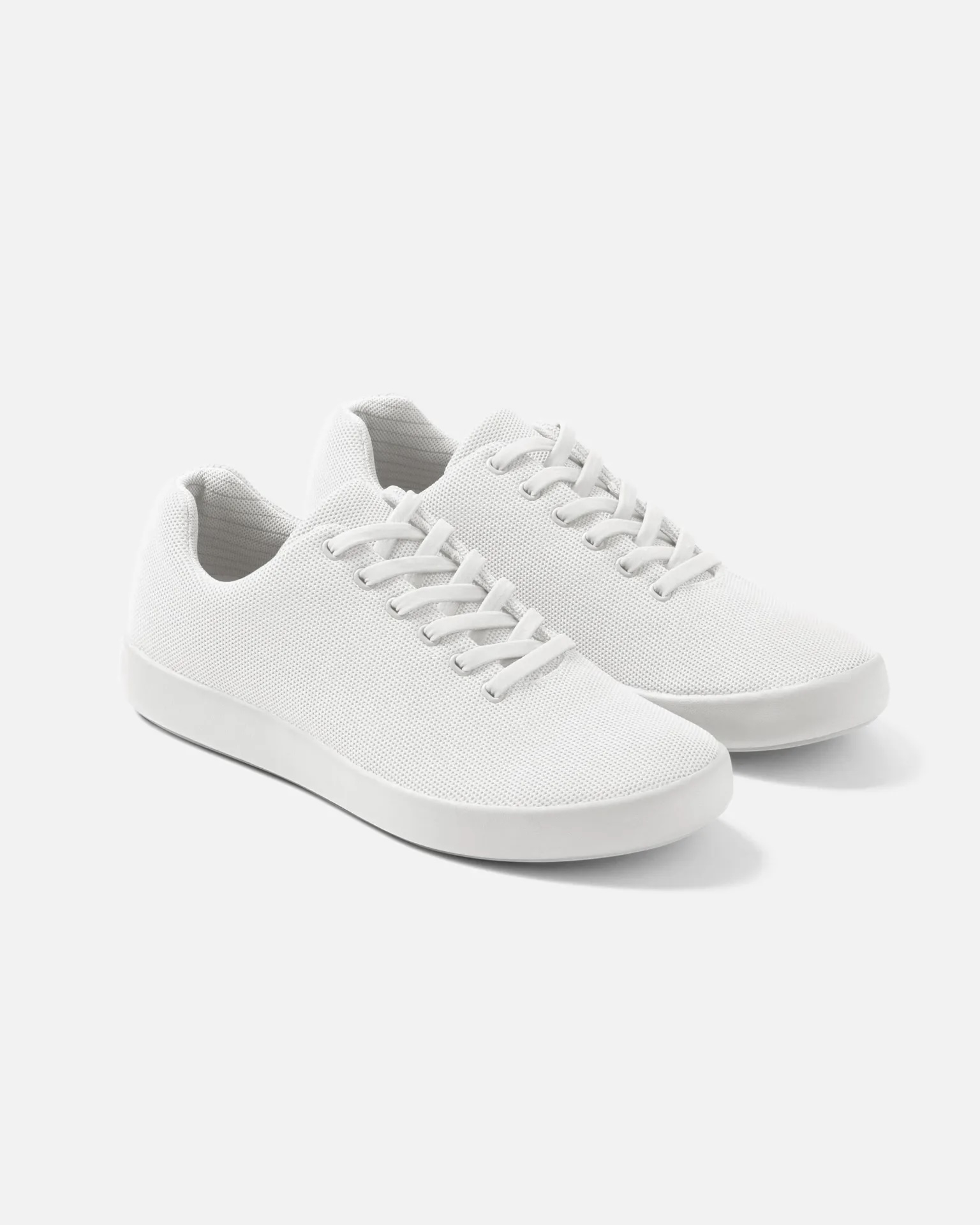 A pair of white lace-up sneakers on a plain background, suitable for versatile styling and shopping options
