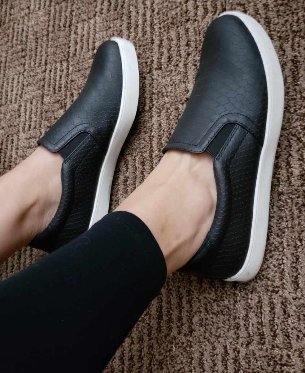 Person wearing black slip-on sneakers, suitable for a comfortable and casual style