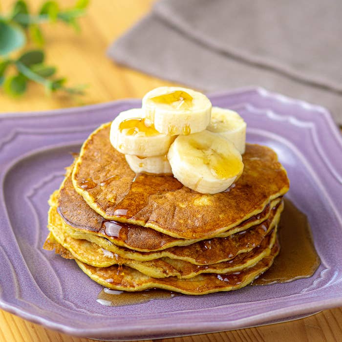 バナナとメープルシロップをトッピングしたパンケーキが皿に盛られています。
