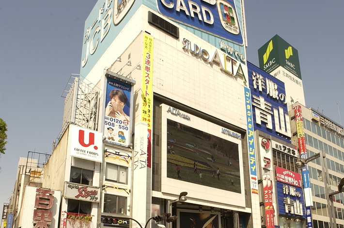 交差点を渡る人々と広告看板がある都市の風景。