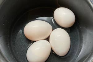 黒い鍋に入った四つの白い卵。