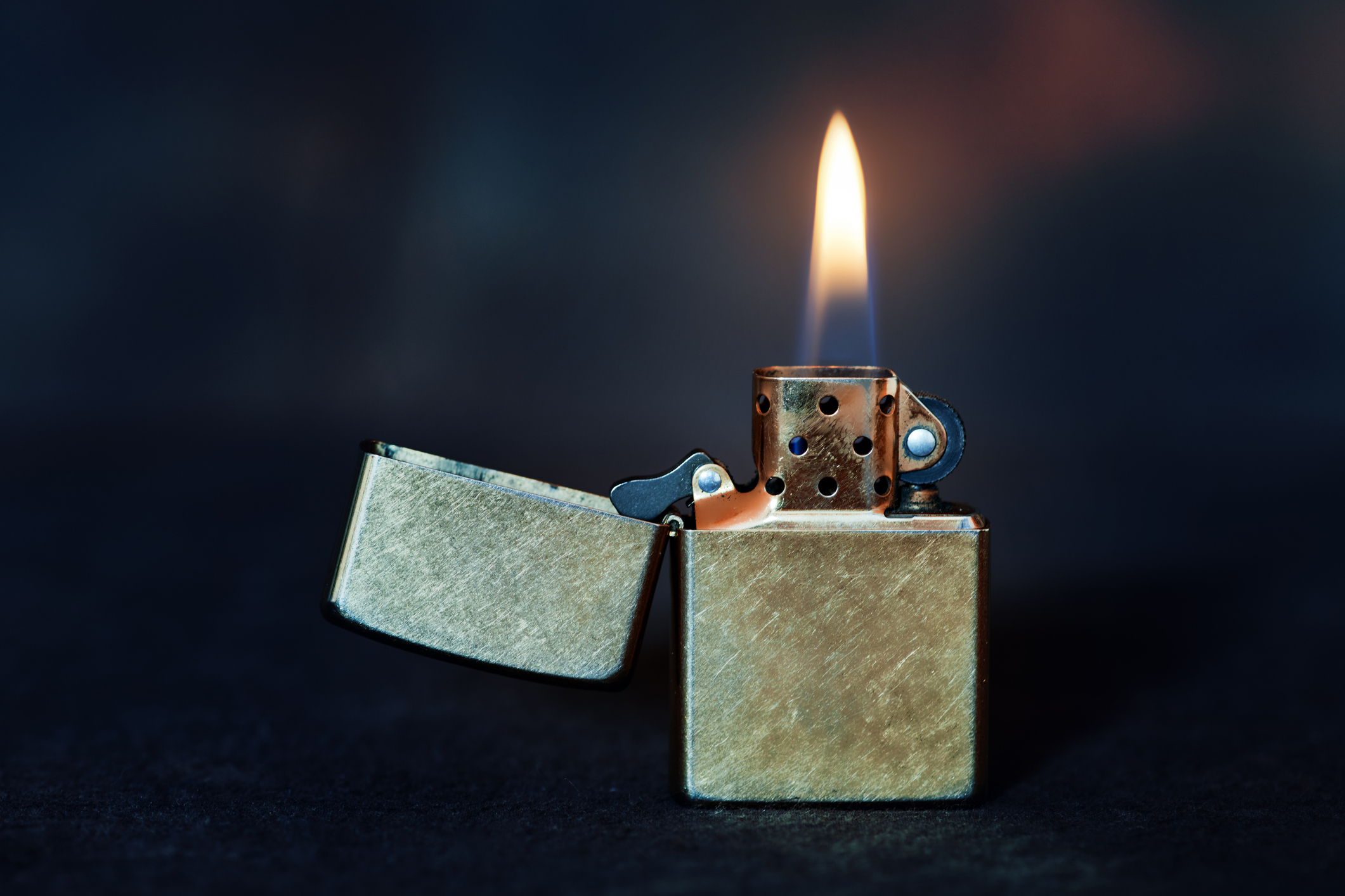 Metal lighter with flame against a dark background