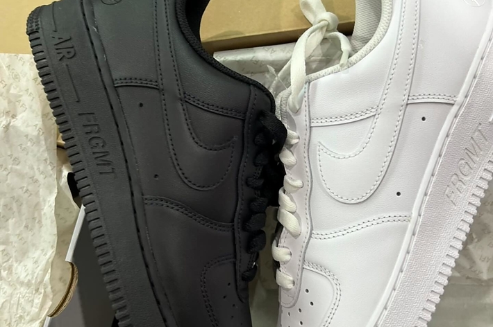 A pair of Nike Air Force 1 sneakers, one black and one white, placed side by side with shoebox in background