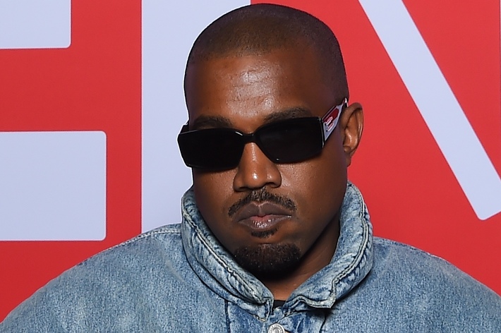 Kanye West in a denim jacket and black sunglasses at an event