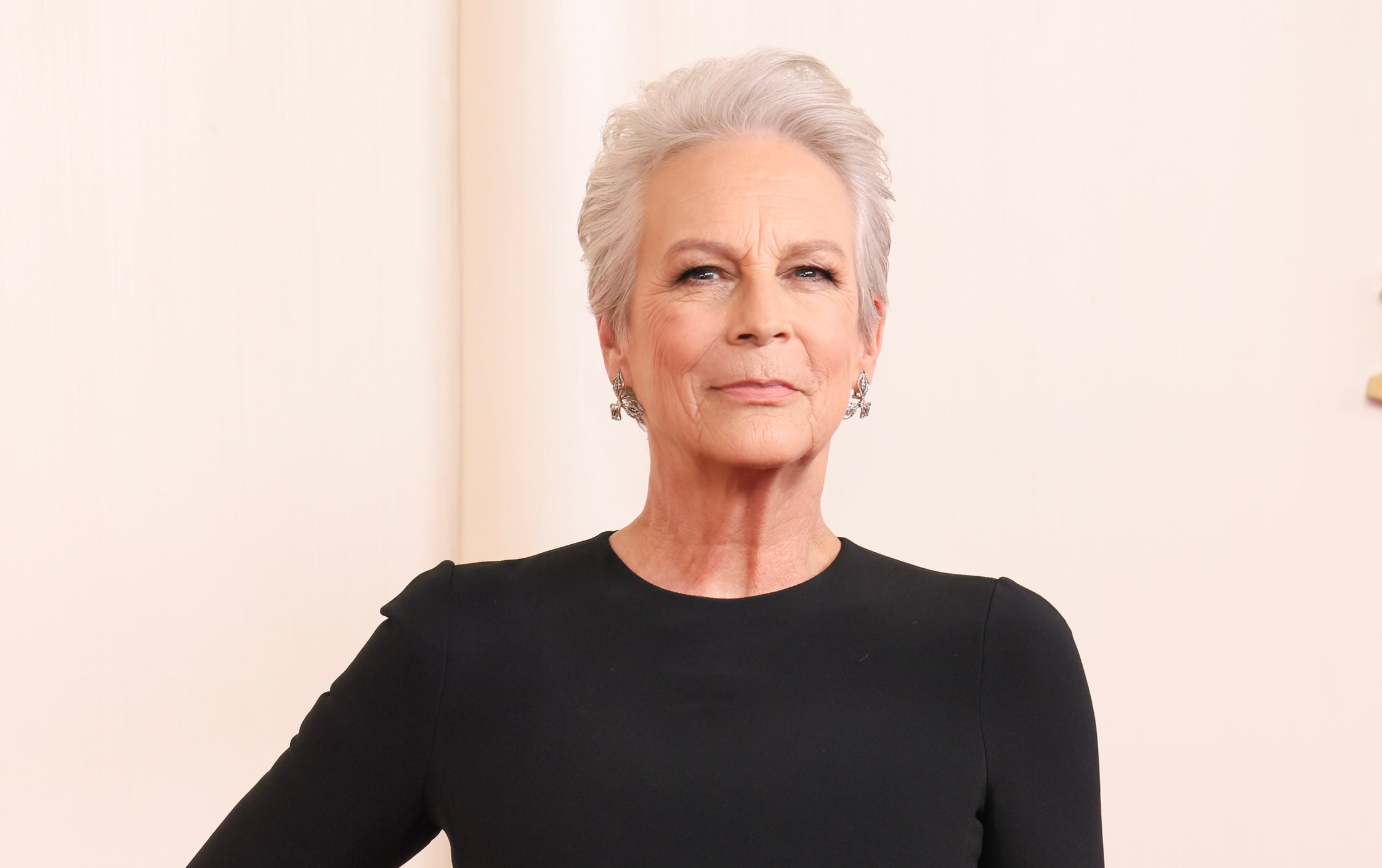 Jamie Lee Curtis wearing a long-sleeved black dress, standing confidently on the red carpet