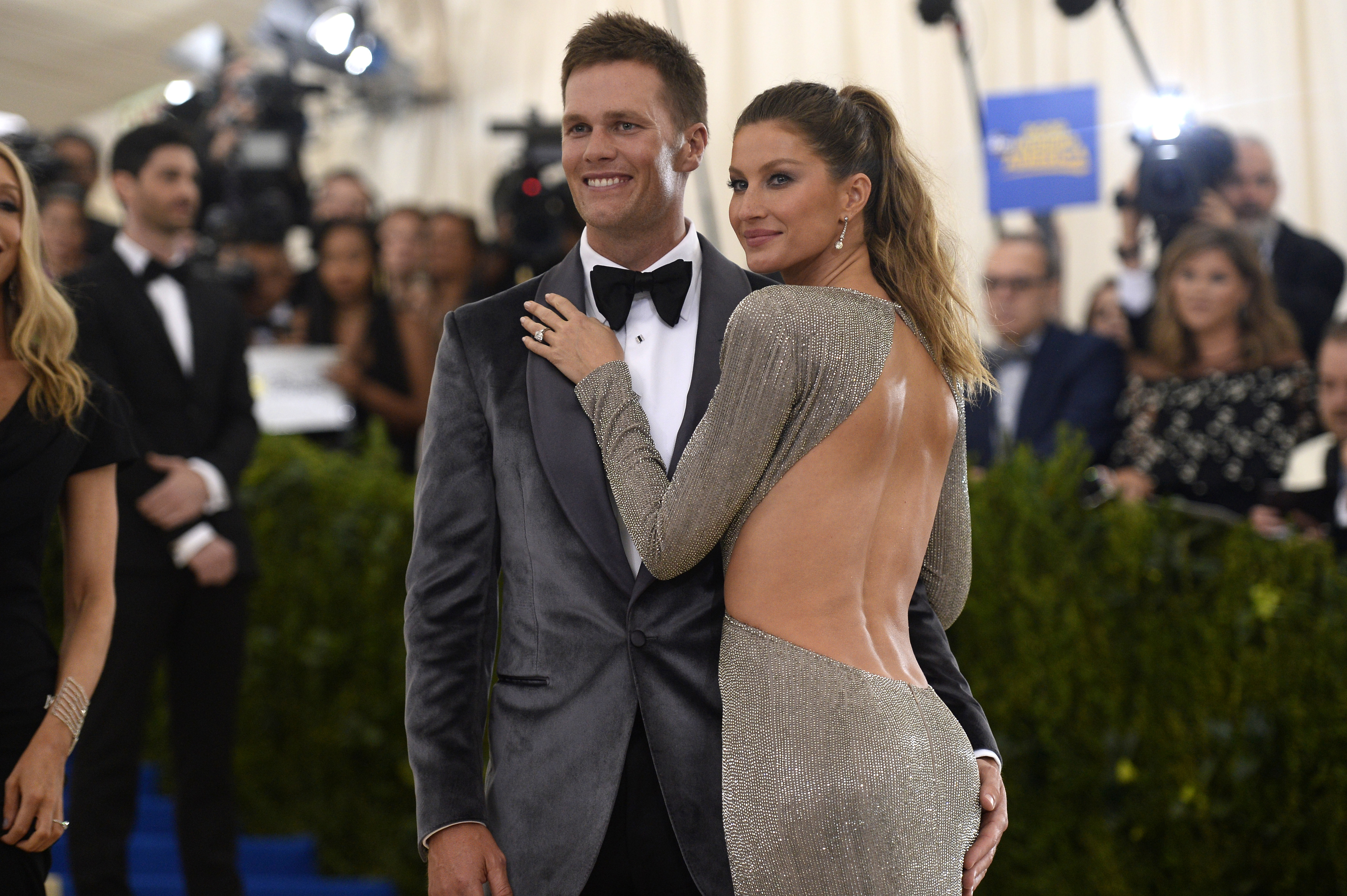 Tom Brady and Gisele Bündchen pose together; he&#x27;s in a suit and bow tie, she wears a backless dress, at a red carpet event