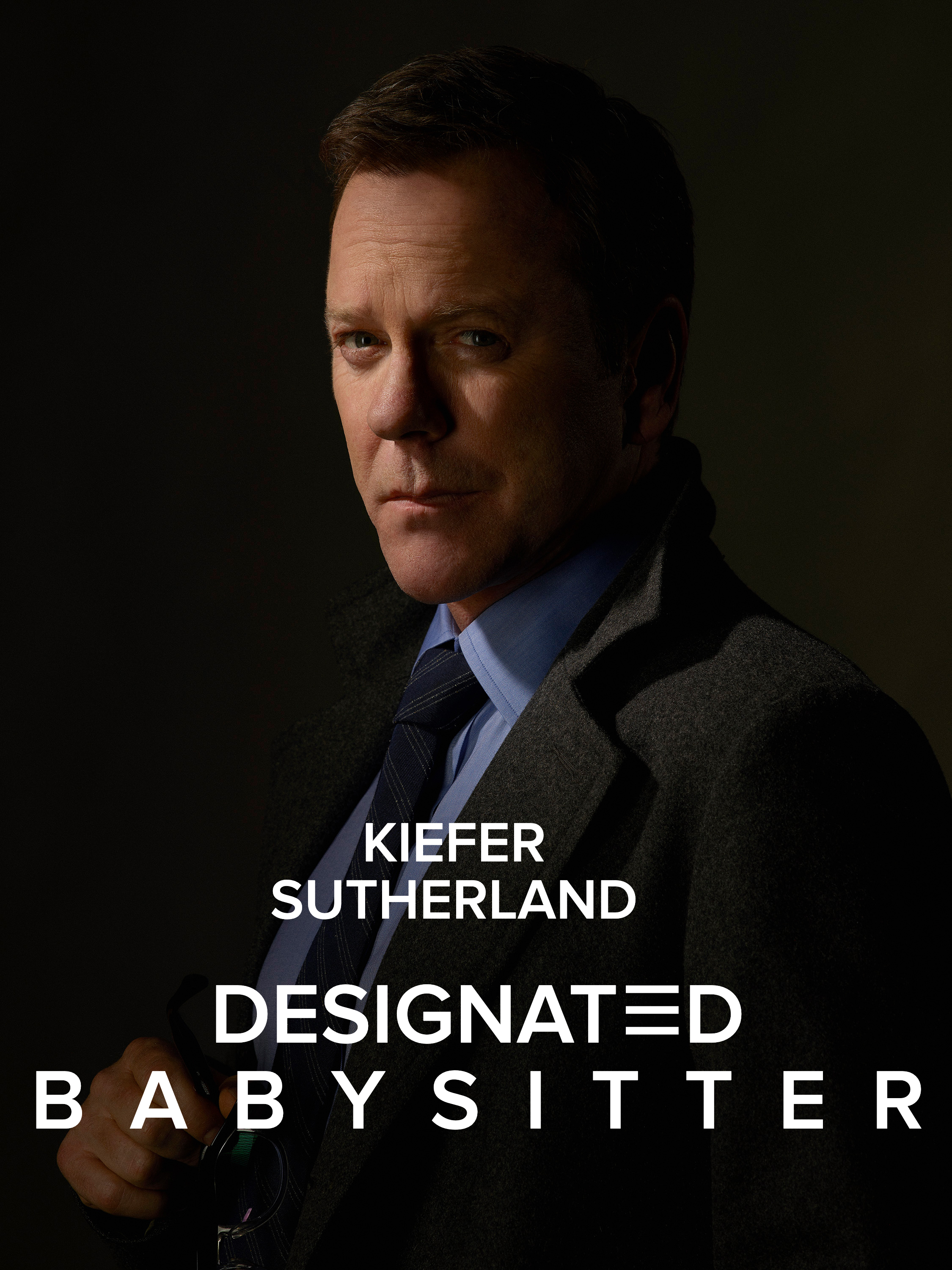 Kiefer in a tailored suit and tie holding glasses, posing with a serious expression, with caption &quot;Kiefer Sutherland Designated Babysitter&quot;