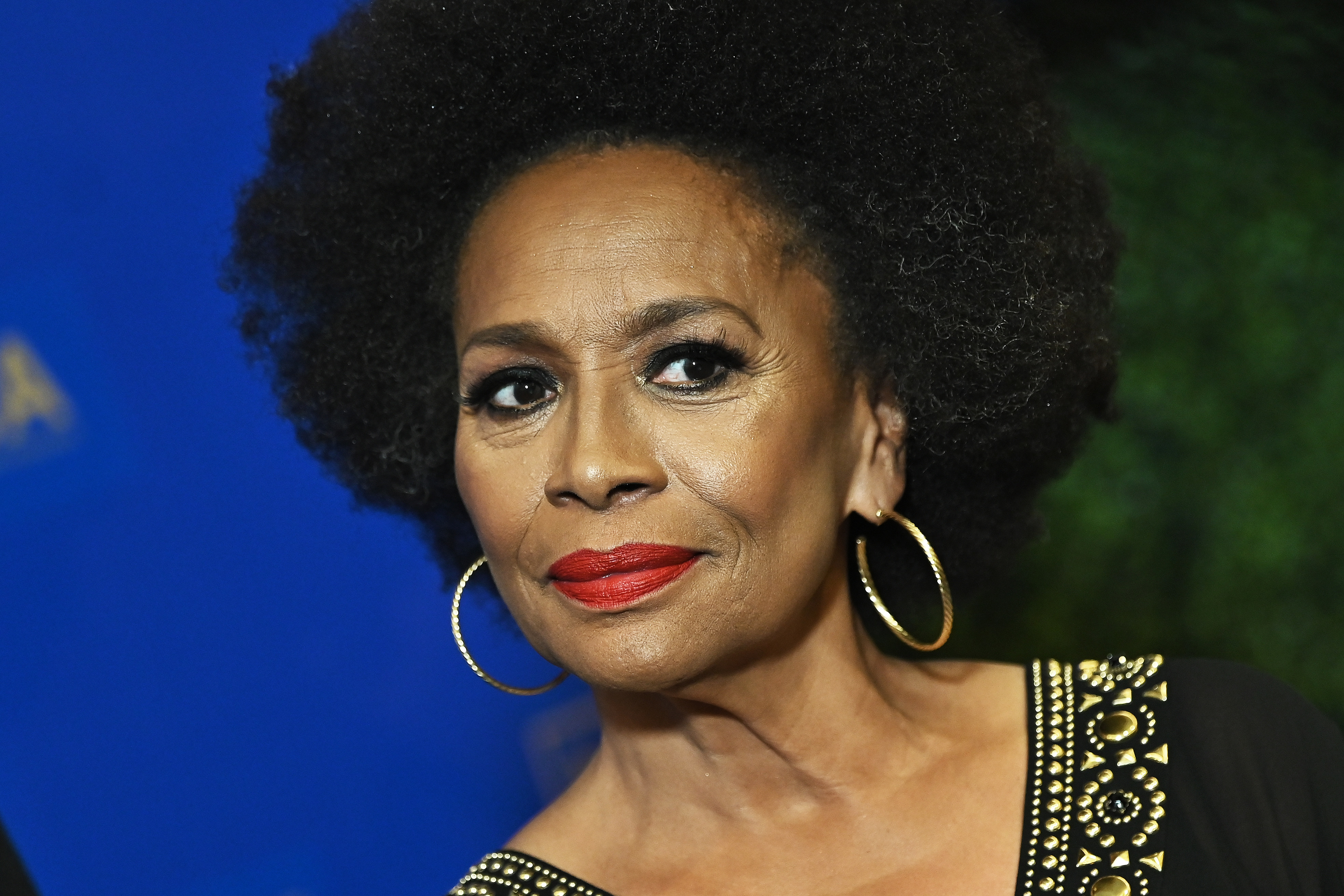 Close-up of Jenifer Lewis wearing hoop earrings and a black top with gold details
