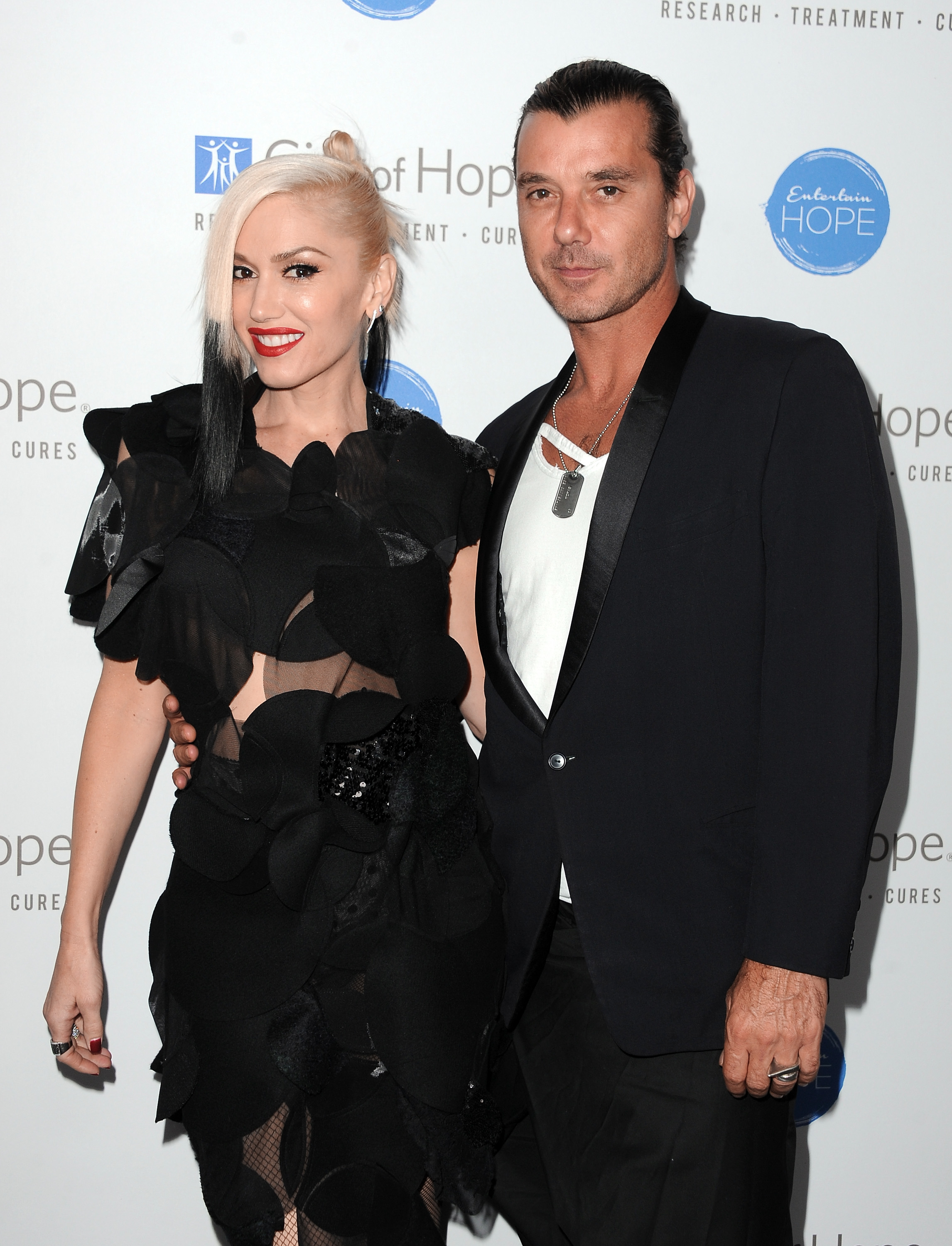 Gwen in a ruffled outfit, and Gavin in a dark suit with a light shirt, at a media event