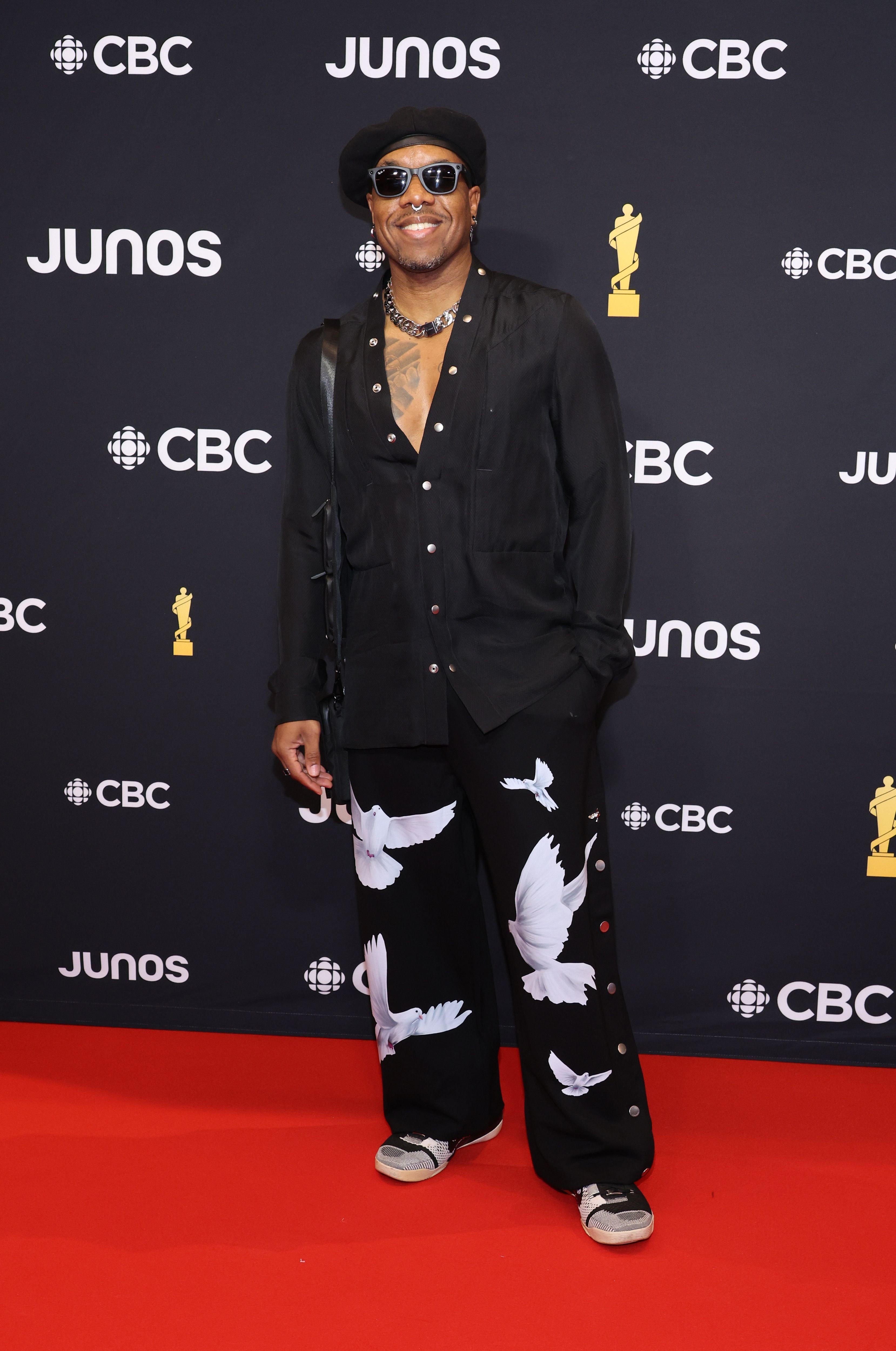 Person in black outfit with white dove print on red carpet at JUNOS event