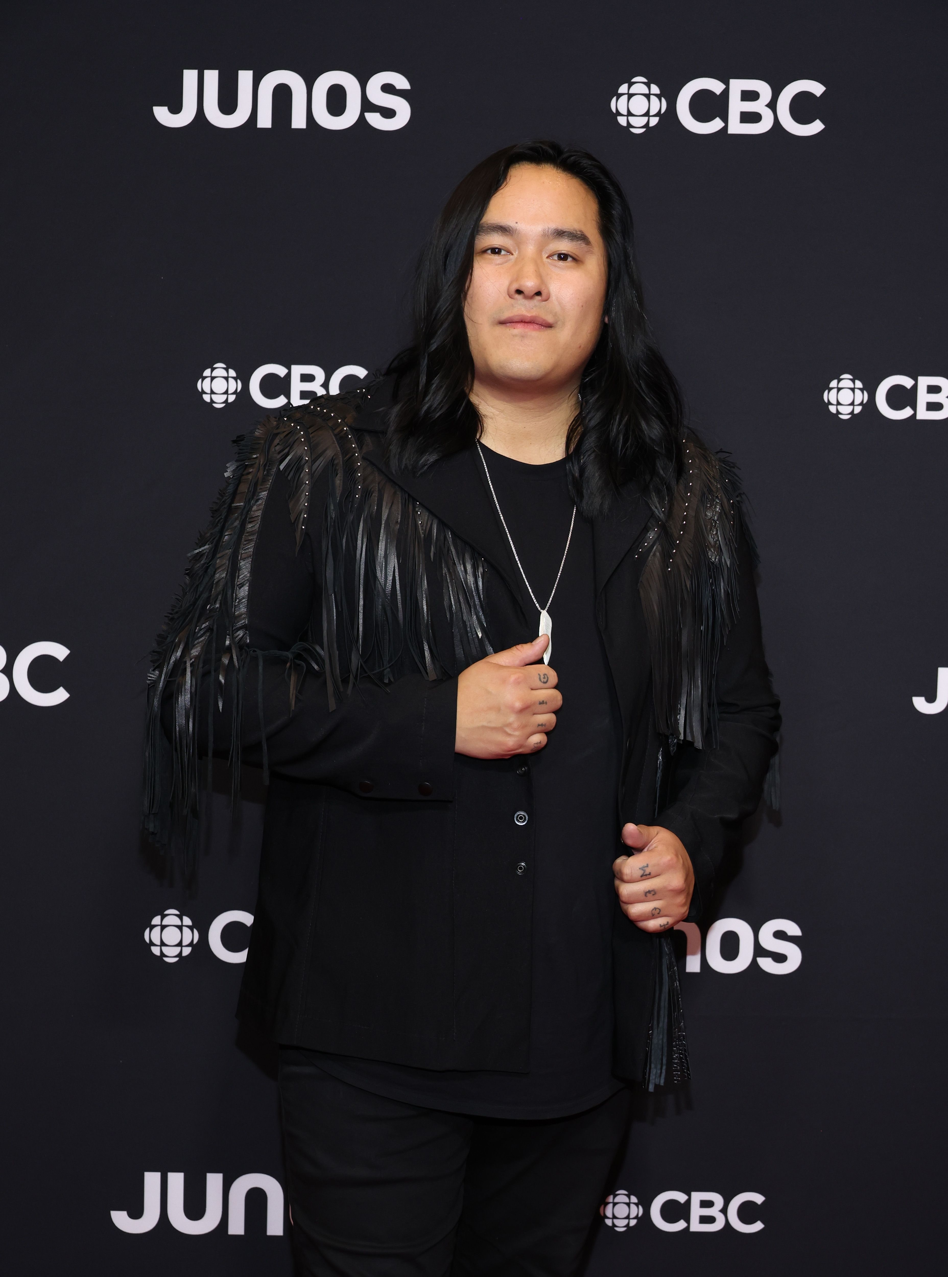 Person in black attire with feathered accents posing at the JUNOS CBC event