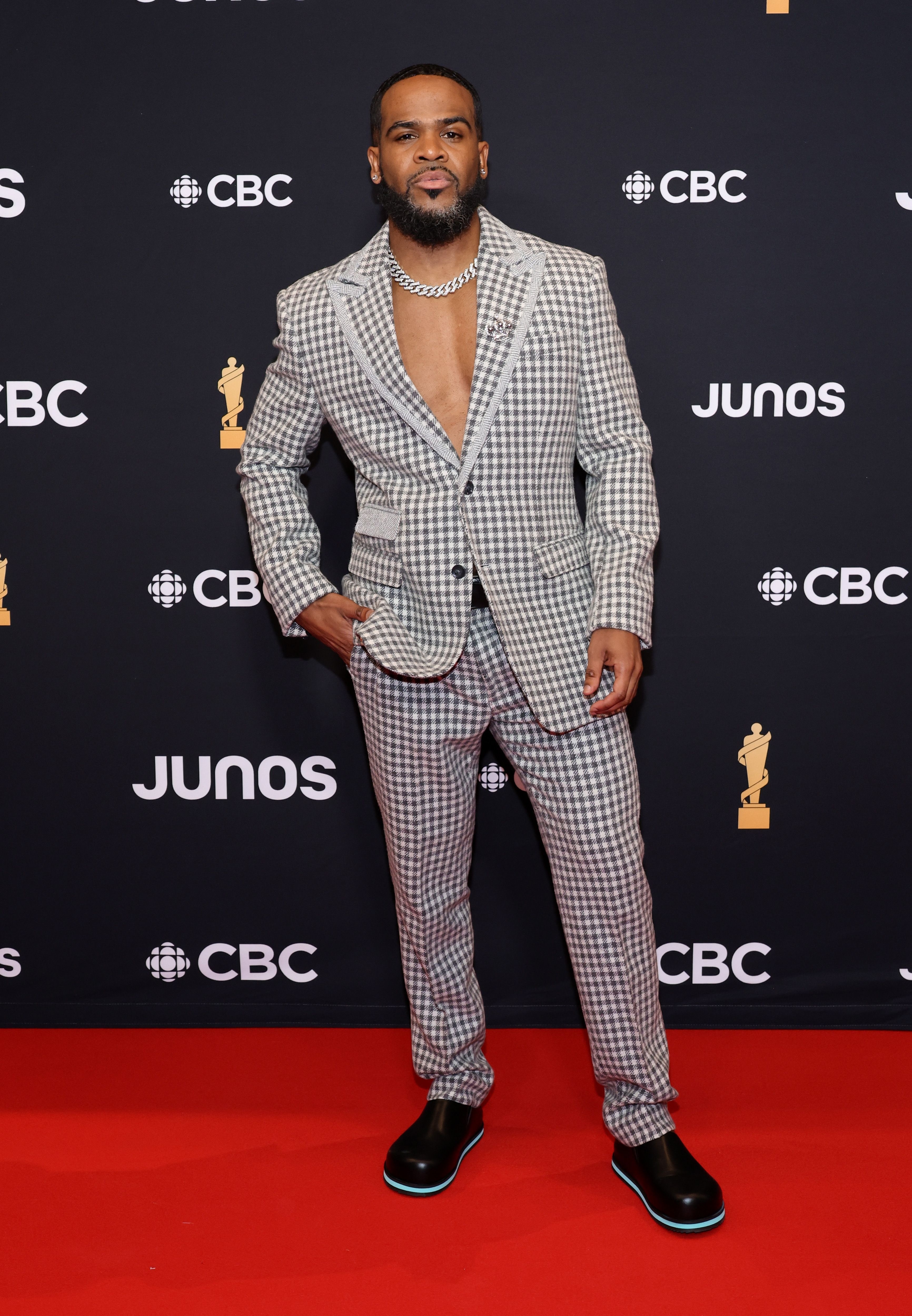 Man in patterned suit poses with hand in pocket at the JUNOS event