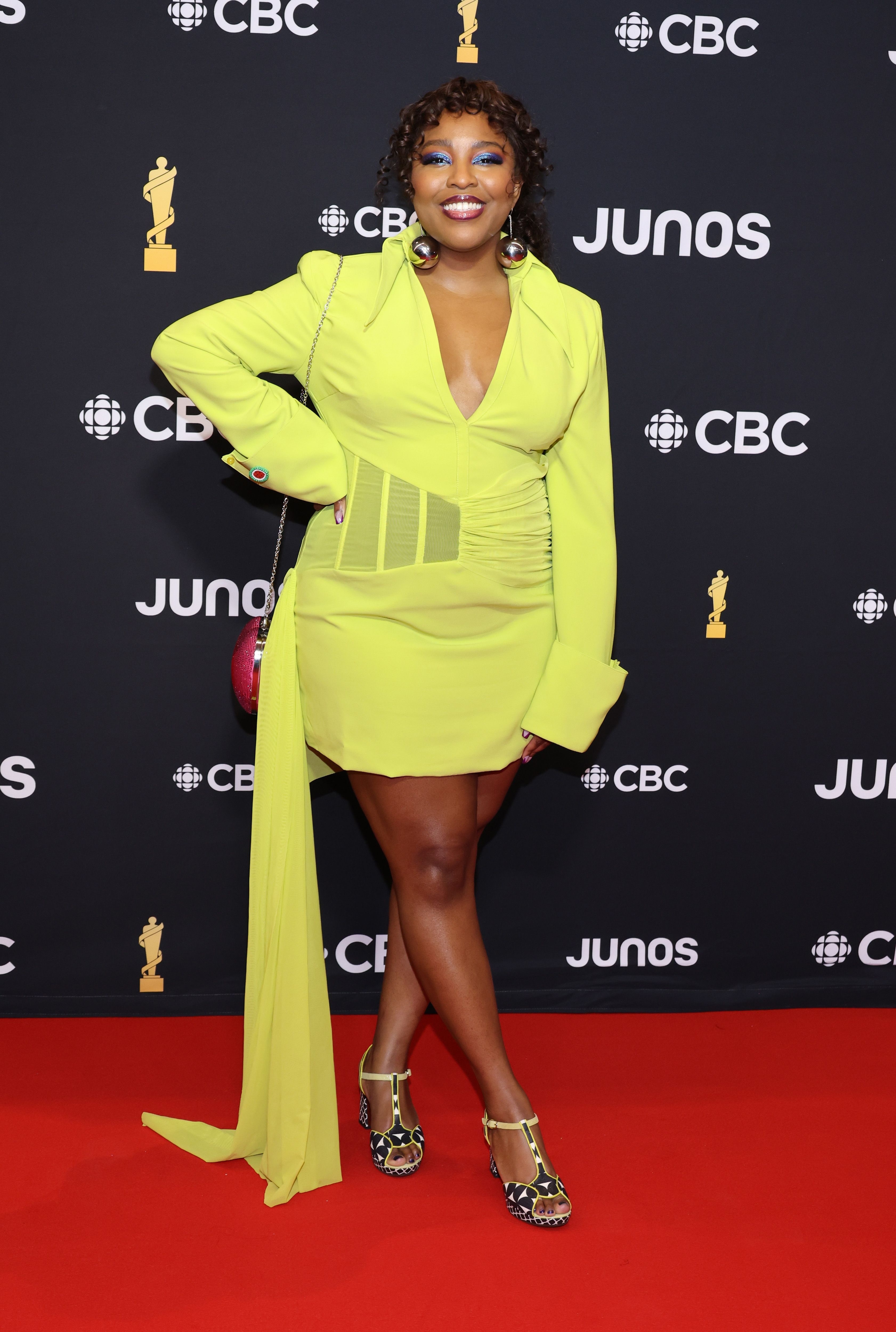 Woman in a neon green dress with cutouts, posing on the Juno Awards red carpet