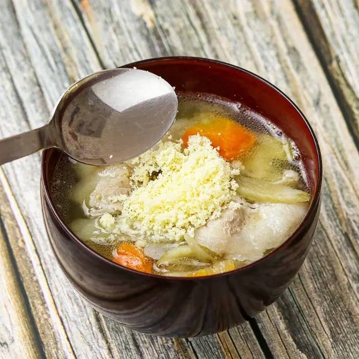 豚汁にパルメザンチーズを加える手元