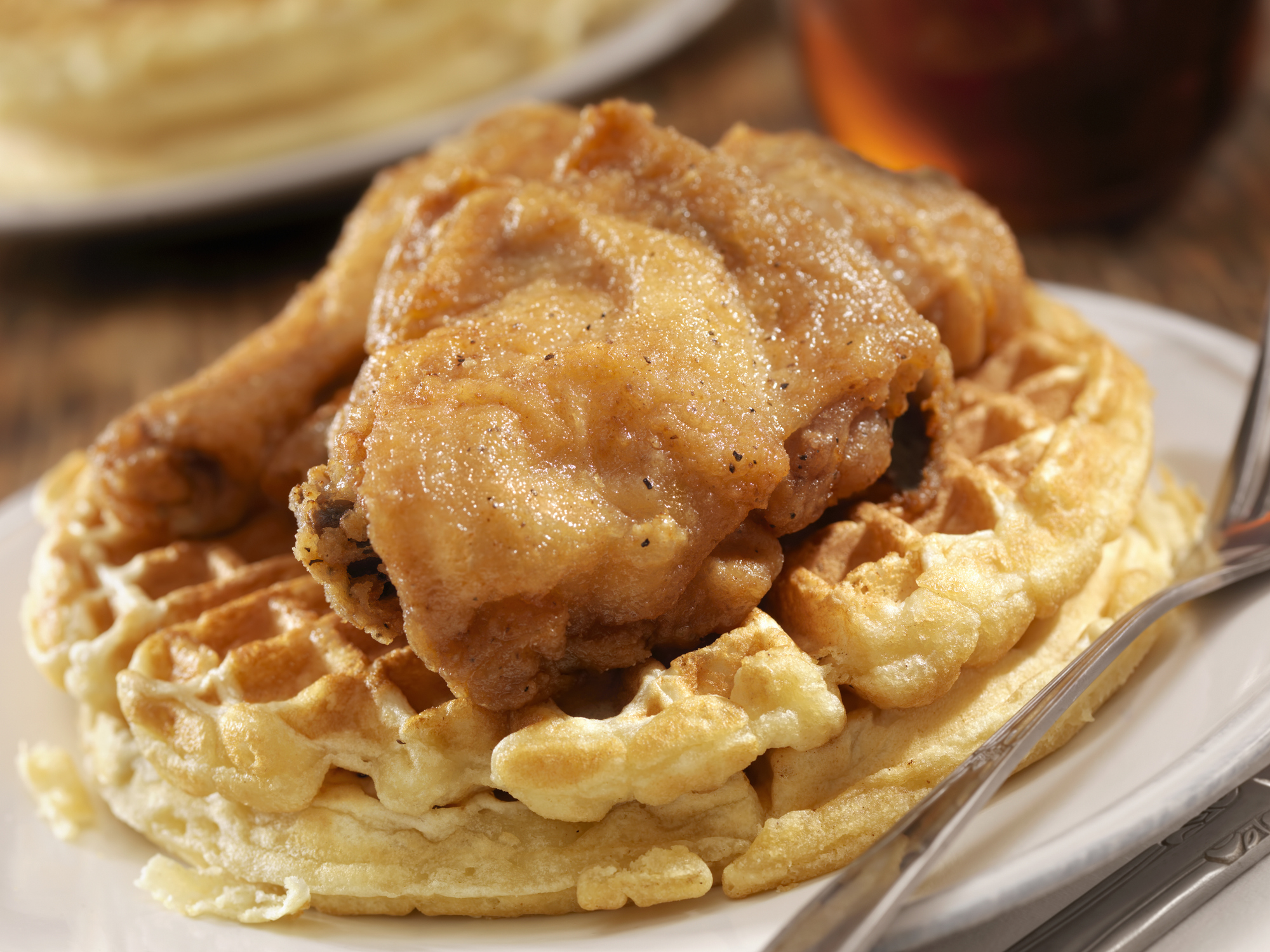 Fried chicken on a waffle with syrup on the side, commonly known as chicken and waffles