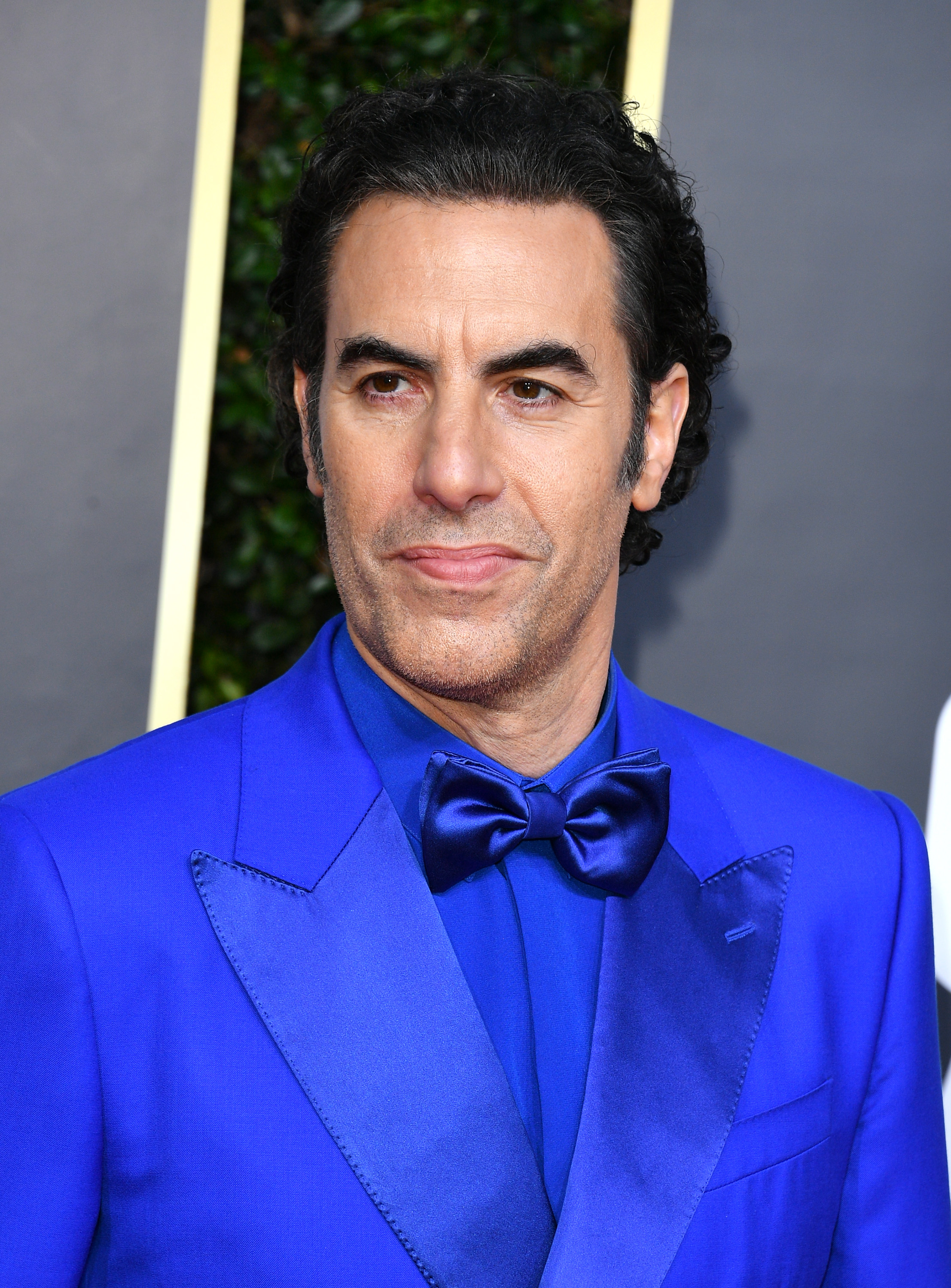Sacha in a blue suit with a bow tie at an event