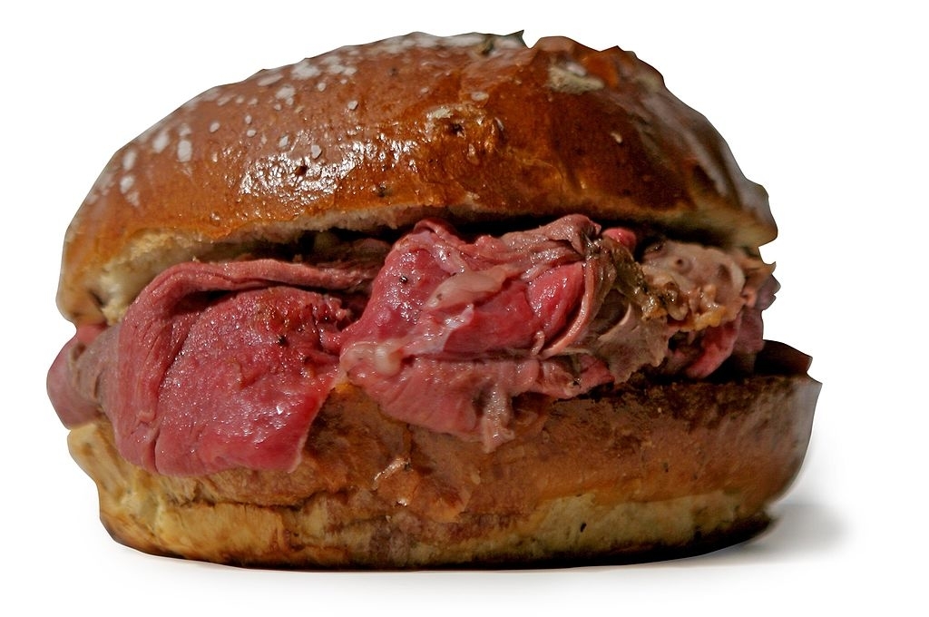 A roast beef sandwich with a thick layer of meat on a sesame seed bun