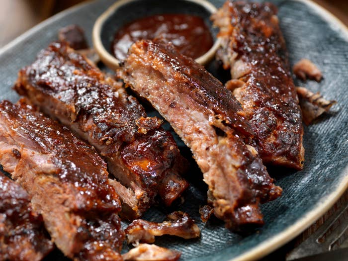 A plate of barbecue ribs with a side of sauce