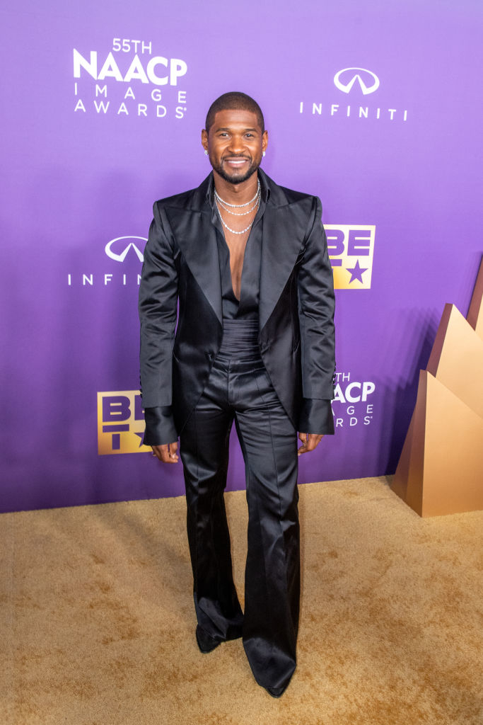 Usher smiling in a black suit posing on the NAACP Image Awards