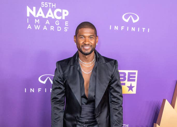 Usher smiling in a black suit posing on the NAACP Image Awards