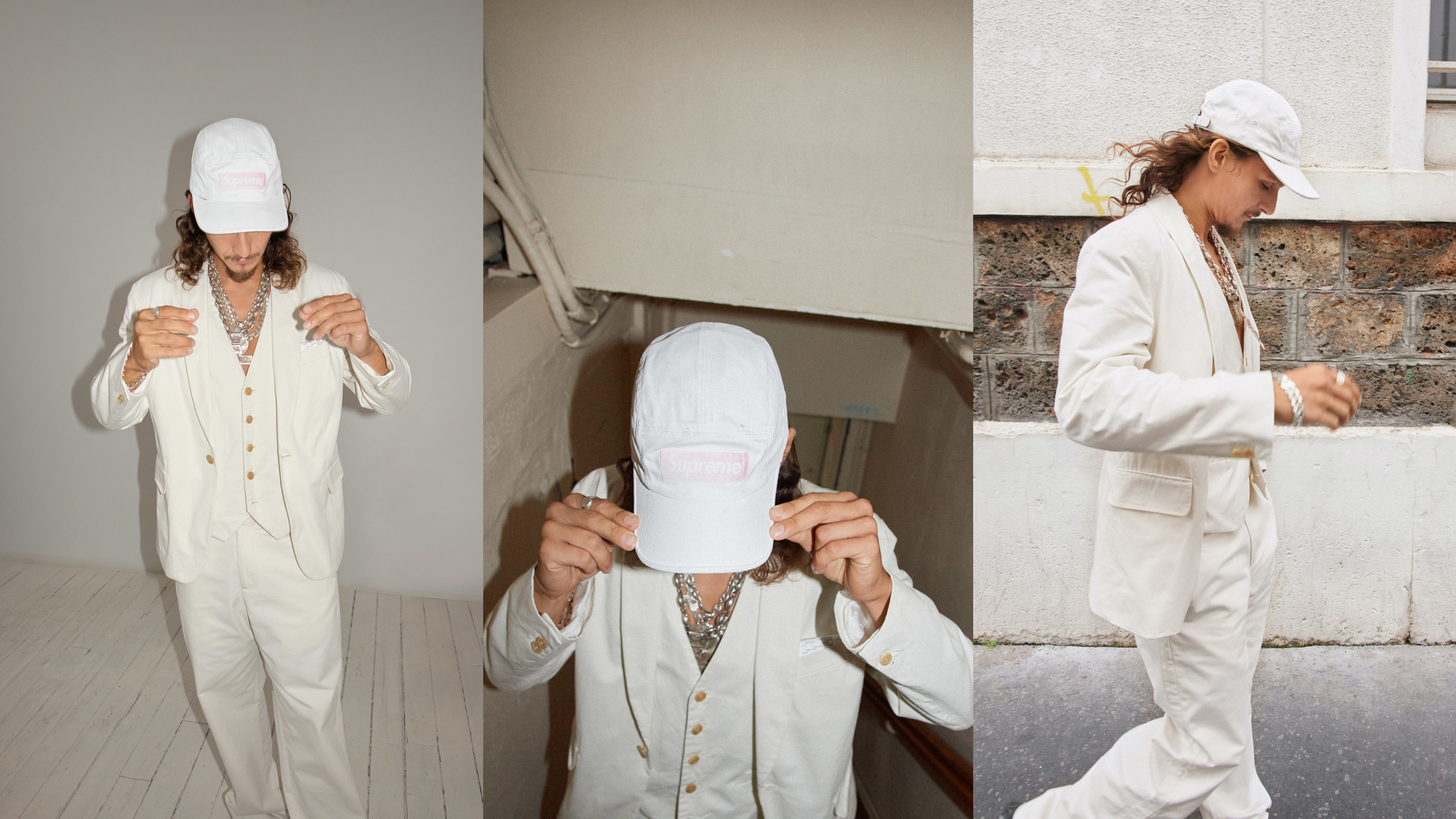 Three poses of a person in a stylish cream suit and hat with layered necklaces, indoors