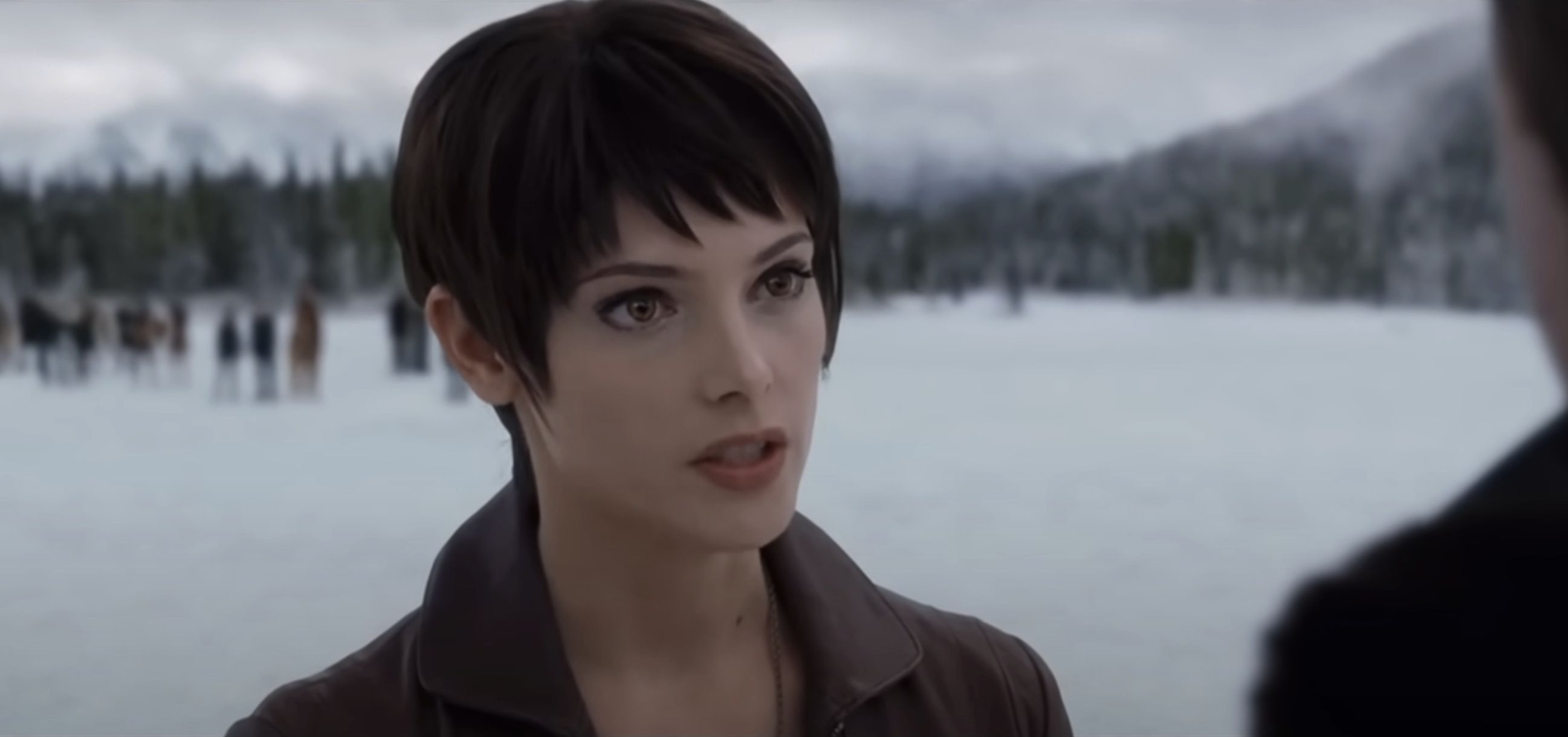 Alice Cullen from Twilight stands in a snowy setting, facing another character
