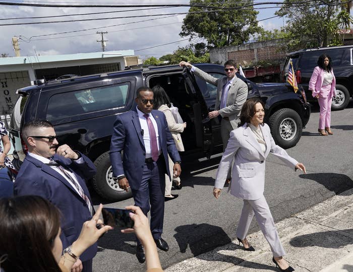 Vice President Kamala Harris exits a vehicle with security detail and onlookers during an official visit