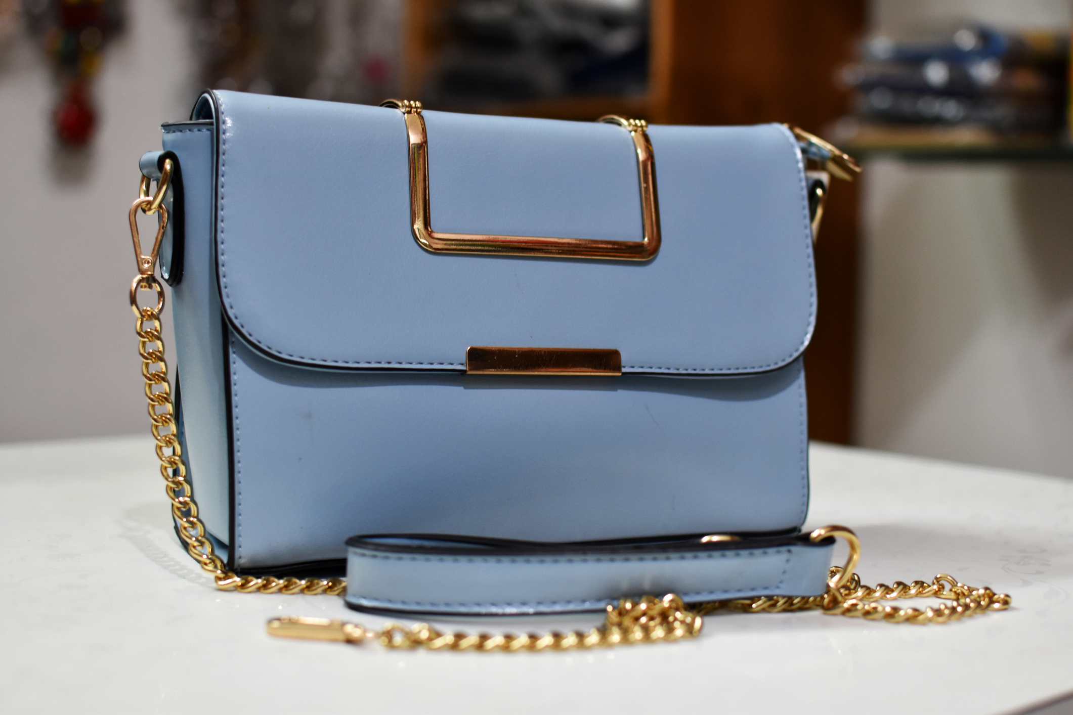 Light blue handbag with gold chain on surface