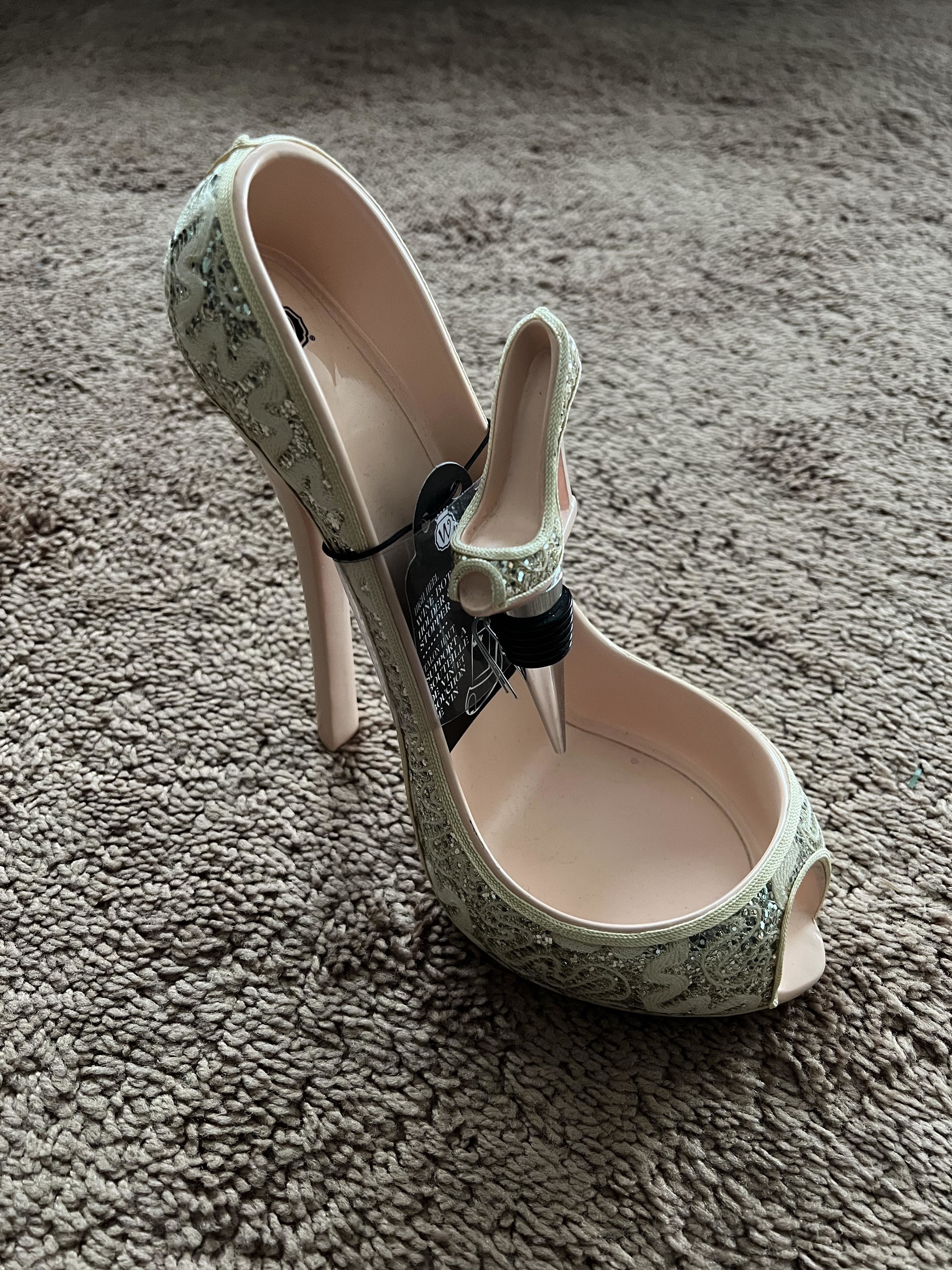 A single high-heel shoe with ornate design, with security tag attached, on a carpeted floor