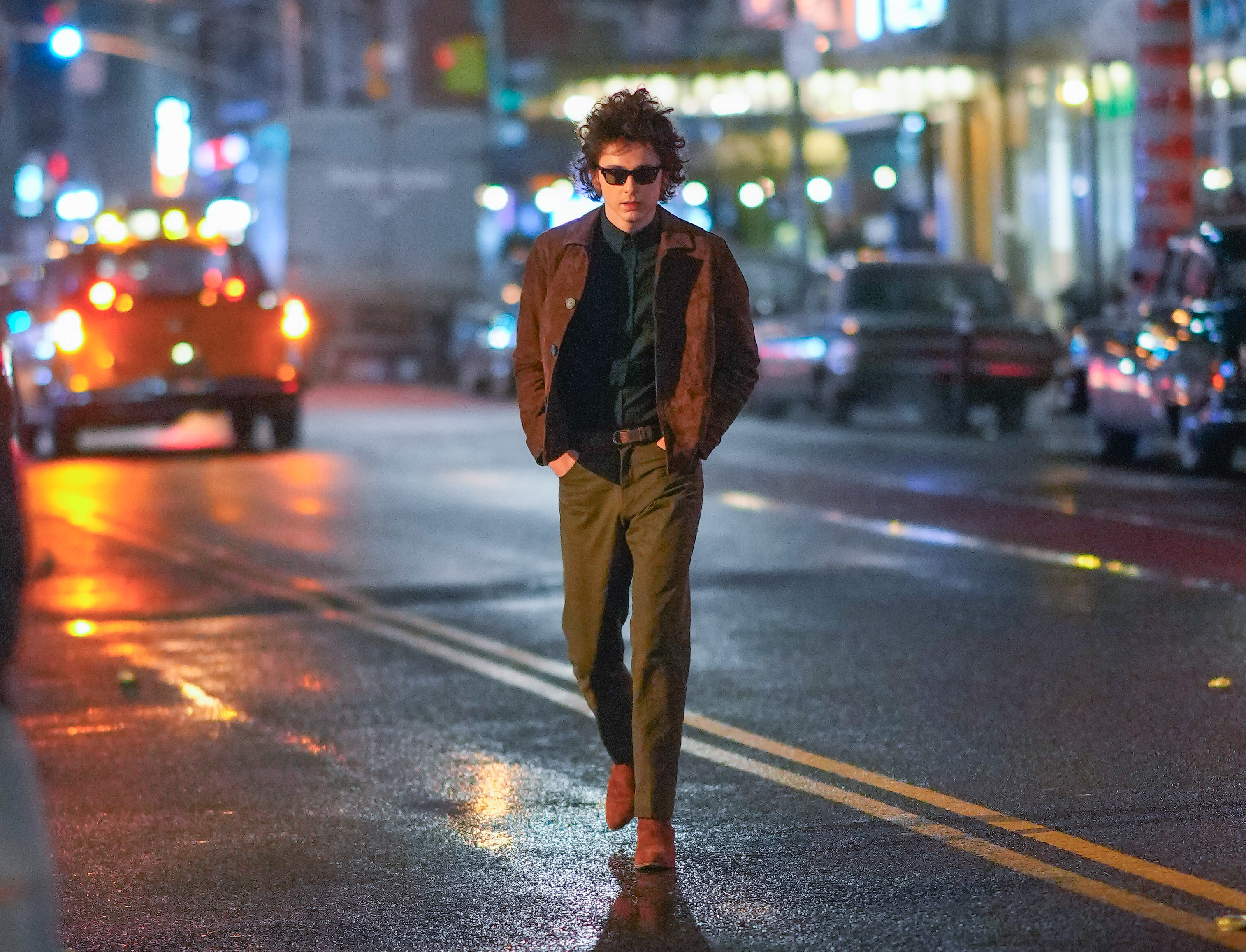 Timmy in jacket and sunglasses walking confidently on urban street at night