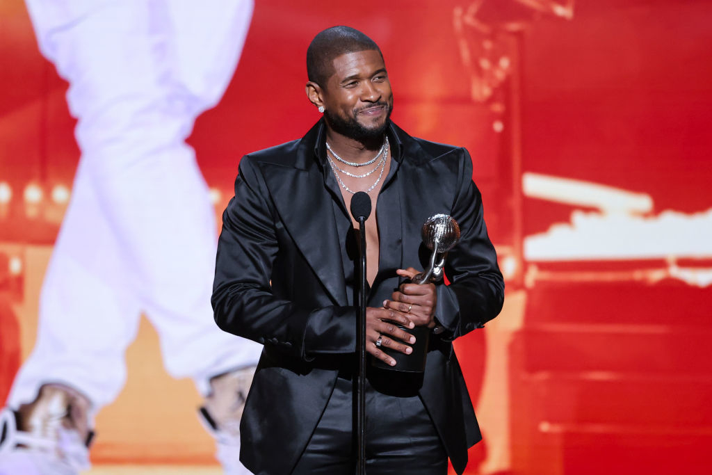 Usher in a black suit holds an award onstage