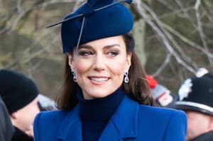 Kate Middleton in a blue coat and matching hat adorned with earrings, smiling at an event